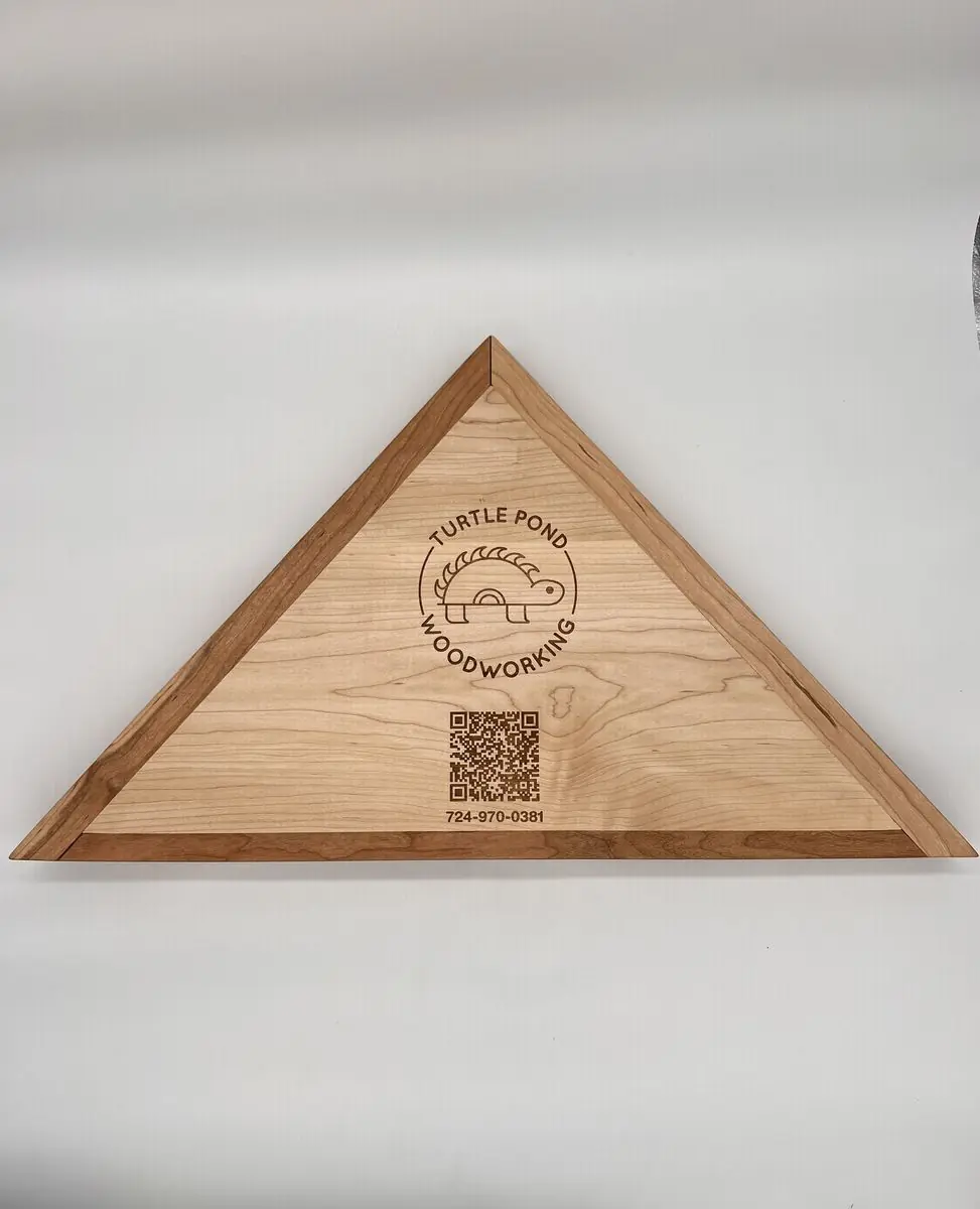 Back of a triangular flag case with an engraved Turtle Pond Woodworking logo, QR code and phone number