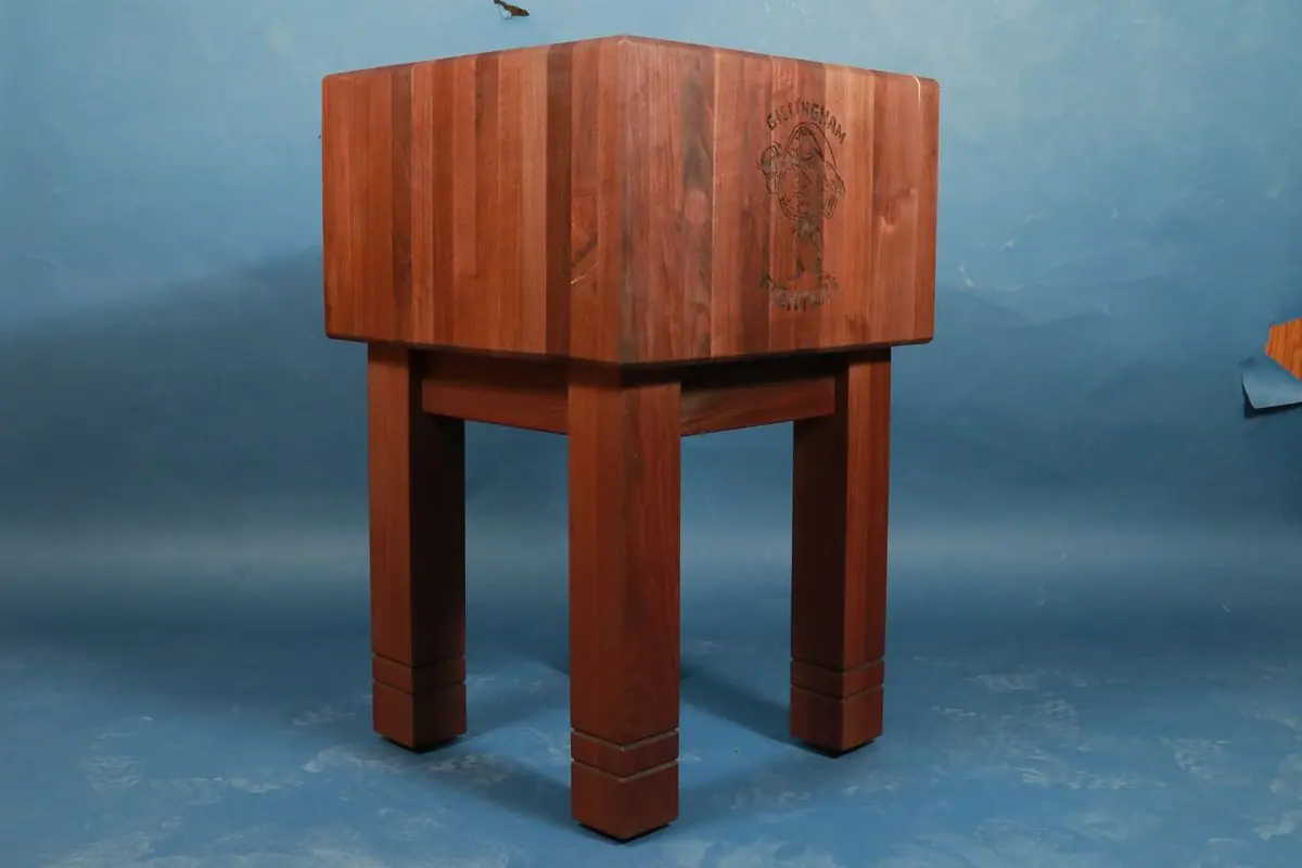 Butcher block on four square legs with an engraved mascot on the side, against a blue backdrop