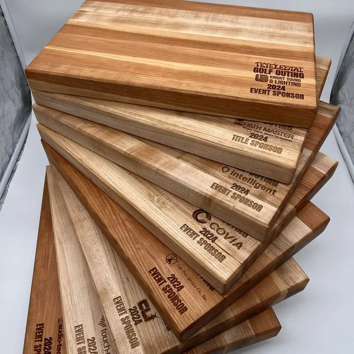 Fanned stack of hardwood cutting boards, each engraved with a sponsor logo and the words 2024 Event Sponsor