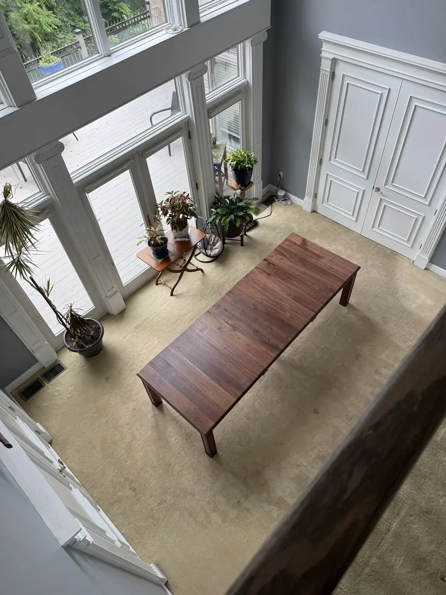 Overhead view of a long dark wood table in a two-story room with tall windows