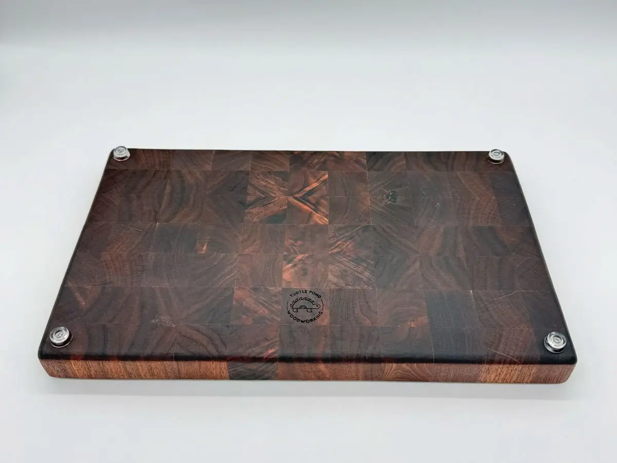 Walnut end-grain cutting board with four clear feet and an engraved Turtle Pond Woodworking logo